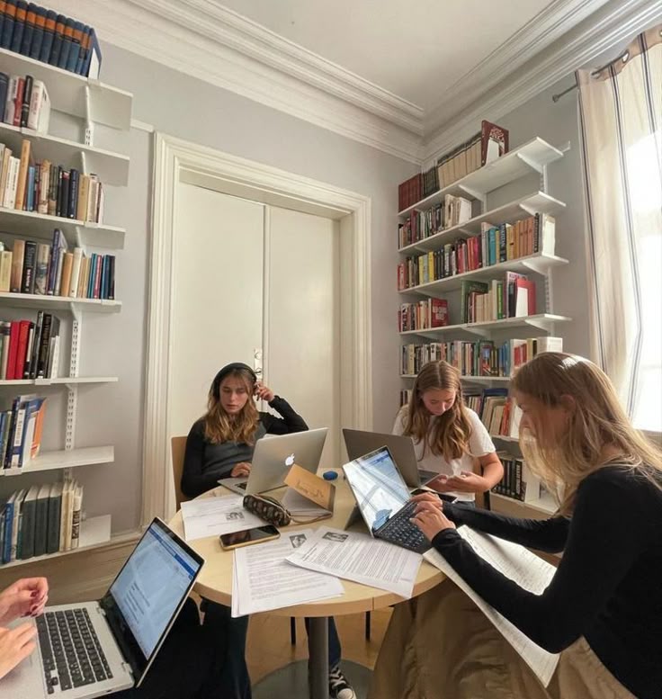 Vier Erstsemester-Studierende lernen gemeinsam an einem Tisch, tauschen Notizen aus und arbeiten konzentriert an ihren Studienunterlagen. Perfekte Darstellung eines erfolgreichen Studienstarts.